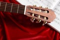 Acoustic guitar and music notes on red velvet fabric, close view of objects Royalty Free Stock Photo