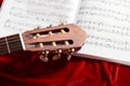 Acoustic guitar and music notes on red velvet fabric, close view of objects Royalty Free Stock Photo