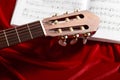 Acoustic guitar and music notes on red velvet fabric, close view of objects Royalty Free Stock Photo