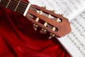 Acoustic guitar and music notes on red velvet fabric, close view of objects Royalty Free Stock Photo