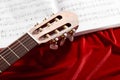 Acoustic guitar and music notes on red velvet fabric, close view of objects Royalty Free Stock Photo