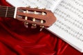 Acoustic guitar and music notes on red velvet fabric, close view of objects Royalty Free Stock Photo