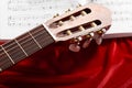 Acoustic guitar and music notes on red velvet fabric, close view of objects Royalty Free Stock Photo