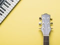 Acoustic guitar neck and piano keys on a yellow background Royalty Free Stock Photo