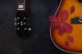 Acoustic guitar and red autumn leaves on dark brown background