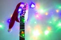 acoustic guitar with red Santa hat and light colorful garland. Christmas music concept