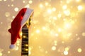 Acoustic Guitar with red Santa hat and light garland. Christmas music song concept with copyspace Royalty Free Stock Photo