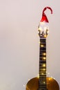 Acoustic Guitar with red Santa hat and light garland. Christmas music song concept with copyspace Royalty Free Stock Photo