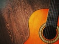 Acoustic guitar resting against a wooden background with copy space