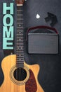 Acoustic guitar, speaker and word Home on a black background, top view. Royalty Free Stock Photo