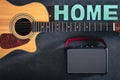 Acoustic guitar, speaker and word Home on a black background, top view. Royalty Free Stock Photo