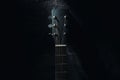An acoustic guitar stands against the wall against a dark background. Background Royalty Free Stock Photo