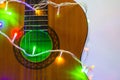 Acoustic guitar wrapped by colorful garland. christmas and new year music gift Royalty Free Stock Photo