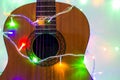 Acoustic guitar wrapped by colorful garland. christmas and new year music gift Royalty Free Stock Photo