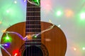 Acoustic guitar wrapped by colorful garland. christmas and new year music gift Royalty Free Stock Photo