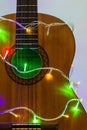 Acoustic guitar wrapped by colorful garland. christmas and new year music gift Royalty Free Stock Photo