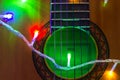 Acoustic guitar wrapped by colorful garland. christmas and new year music gift Royalty Free Stock Photo