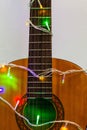 Acoustic guitar wrapped by colorful garland. christmas and new year music gift Royalty Free Stock Photo