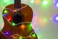 Acoustic guitar wrapped by colorful garland. christmas and new year music gift Royalty Free Stock Photo