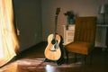 An acoustic Spanish guitar on a stand next to a chair in the moody shadows of a dark room Royalty Free Stock Photo