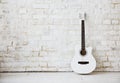 Acoustic white guitar leaning against a white wall in an empty room Royalty Free Stock Photo