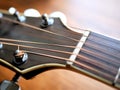 Acoustic wood guitar close up on wooden background with fretboard, strings, and tuners for music blogs, website banners.