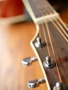 Acoustic wood guitar close up on wooden background with fretboard, strings, and tuners for music blogs, website banners.