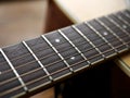 Acoustic wood guitar close up on wooden background with fretboard, strings, and tuners for music blogs, website banners. Royalty Free Stock Photo