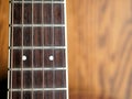 Acoustic wood guitar close up on wooden background with fretboard, strings, and tuners for music blogs, website banners.