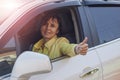 The acquisition of a new car. Happy beautiful girl driving a car, showing thumb up