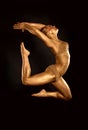 Acrobat dancer toned in gold jumping over black background Royalty Free Stock Photo