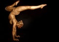 Acrobat dancer toned in gold posing over black background