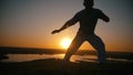 Acrobat makes torsion on the hands, sunset, slow-motion