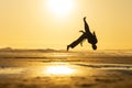 Capoeira practitioner performing backflip on golden beach during sunset Royalty Free Stock Photo