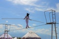 An acrobat tightrope walker walks along a tightrope with a black bag on his head against the sky during an ethno festival