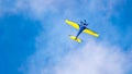 An acrobatic plane, flying in the blue sky with white clouds, doing acrobatics