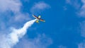 An acrobatic plane, flying in the blue sky with white clouds, doing acrobatics Royalty Free Stock Photo