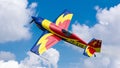 An acrobatic plane, flying in the blue sky with white clouds, doing acrobatics