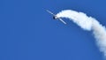Acrobatic plane upside down with white smoke in blue sky with huge copy space Royalty Free Stock Photo