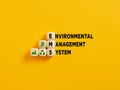 The acronym EMS and Environmental Management Syatem text on wooden cubes on yellow background