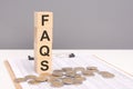 acronym FAQS on wood cubes and coins on background. It suggests accessibility, clarity, and the provision of information Royalty Free Stock Photo