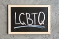 Acronym LGBTQ written on a blackboard, concrete wall as background