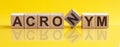 ACRONYM - word from wooden blocks with letters, sorry concept, yellow background