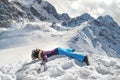 Acrophobia woman in funny mohawk hat lie on top of a snowy rock cliff edge. Fighting the fear of heights concept