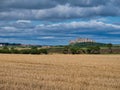 Across fields at harvest time, the imposing Bamburgh Castle dominates views from a dolerite outcrop in Northumberland, UK