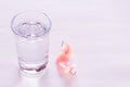 Acrylic dentures immersed in a glass of water, table in the bedro