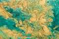 Acrylic fluid art. Abstract golden waves on green background with golden inclusions. Free flowing paint Royalty Free Stock Photo