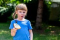 Fussy eater, little girl, picky child eating a slice of bread with butter displeased, choosy kid behavior, doesn`t want to eat