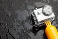 Action camera in a waterproof box and a buoy for diving in water drops on a black background. Copy space for text.