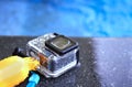 Action camera in waterproof case and floater grip on poolside and blur swimming pool Royalty Free Stock Photo
